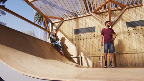 video of happy diverse female and male skateboarders training in skate park