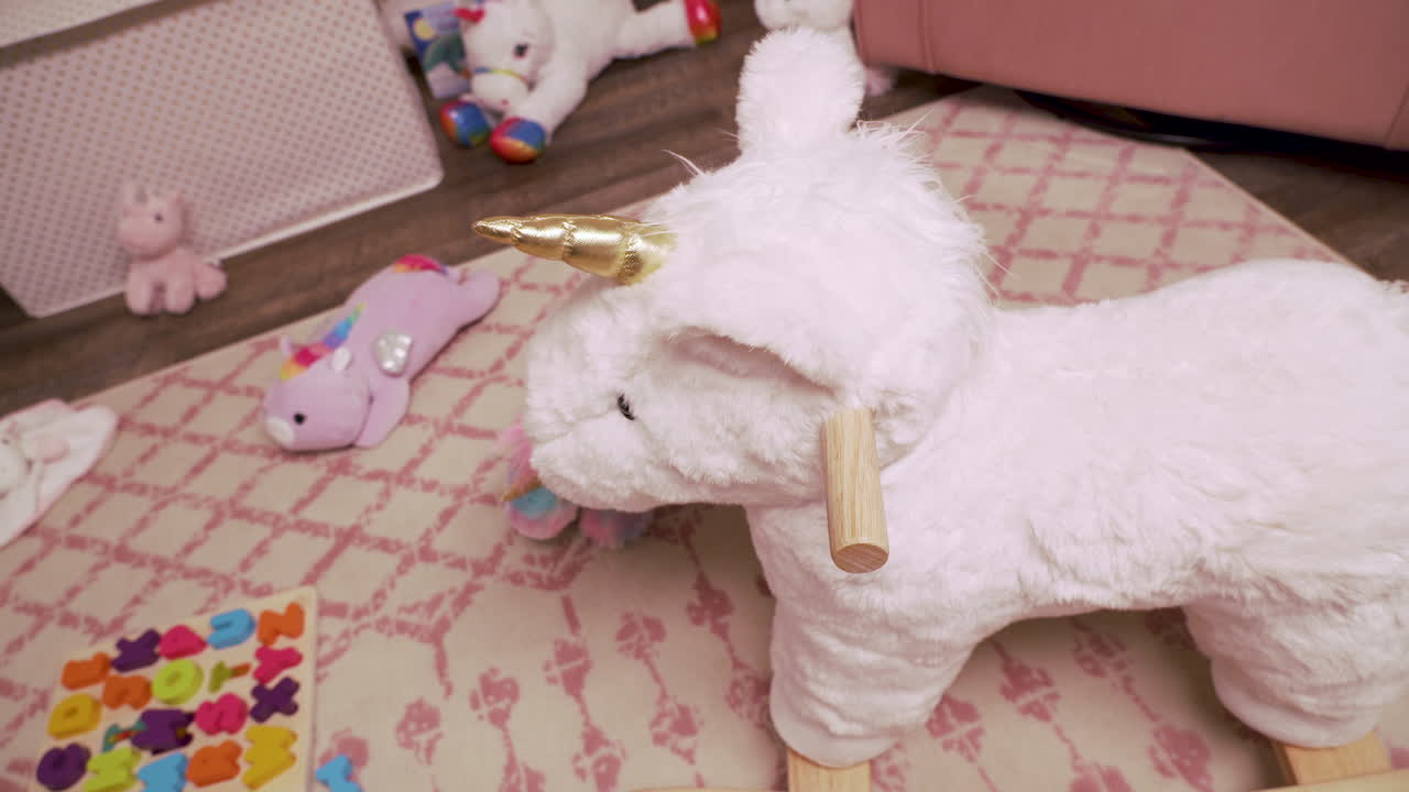 Little Girl Rocking Horse in Little Girl's Room With Stuffed Animals and Pink colors