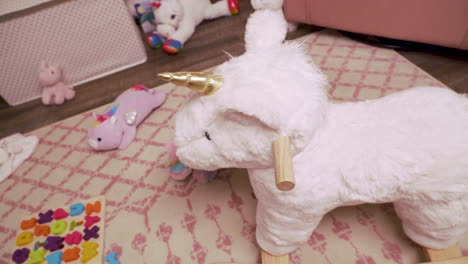 little girl rocking horse in little girl's room with stuffed animals and pink colors