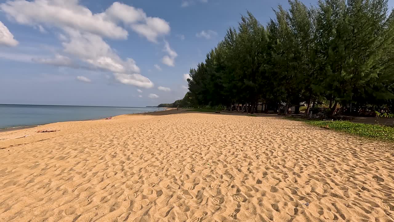 A tranquil beach scene in Phuket with gentle waves, clear skies, and lush greenery