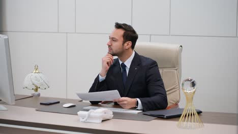 business man reading on computer and analyzing paper reports in modern office