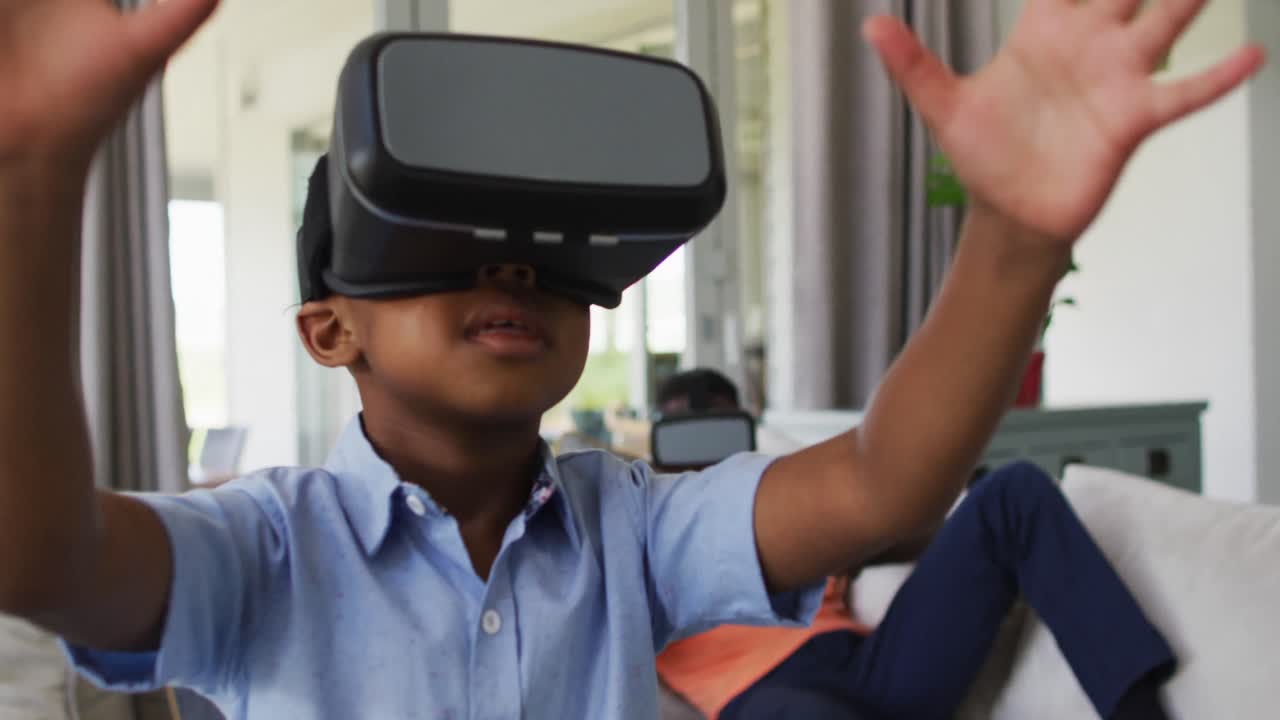 Afroamerikansk far og søn bruger VR-headsets sammen på en sofa