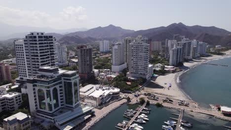 Aerial-orbit-around-skyscrapers,-marina-and-beachfront-in-Santa-Marta,-Colombia