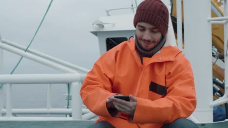 casualy dressed fisherman using mobile phone while traveling on ship.