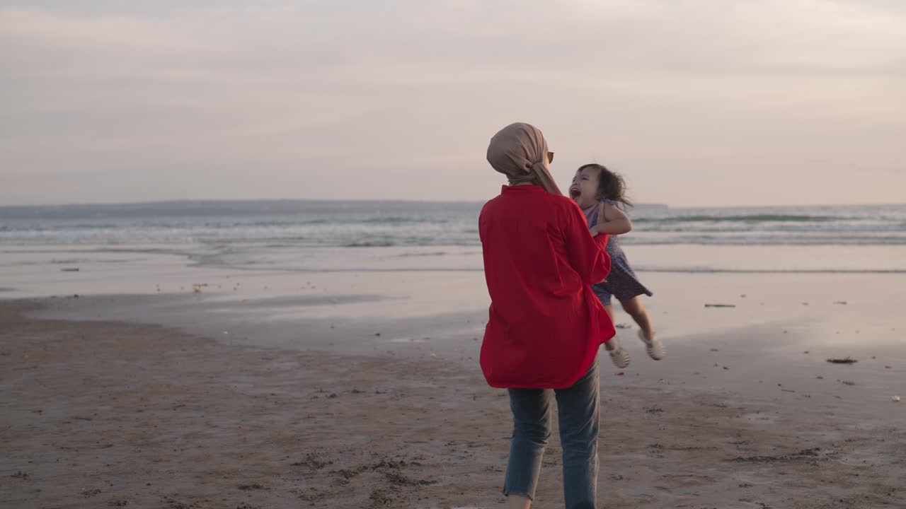 해가 지면 해변에서 놀고 있는 어머니와 딸