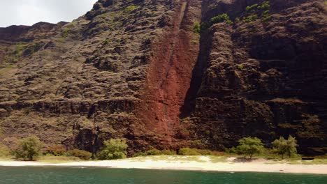 gimbal wide panning shot from a boat of the polihale state park campsites under the steep cliffs of the southern na pali coast on the island of kaua'i in hawai'i