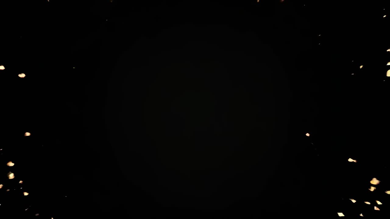 Golden particles form a heart shape on a black background, top-down angle, perfect for romantic