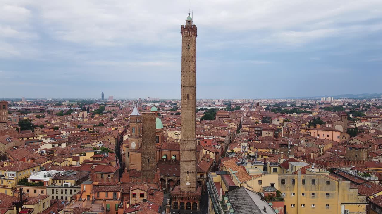 Drone closing in on Bologna’s medieval towers as birds fly on cloudy evening