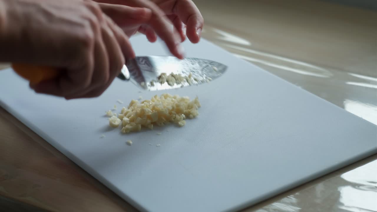 Chopping Fresh Garlic On Cutting Board With Knife. closeup shot