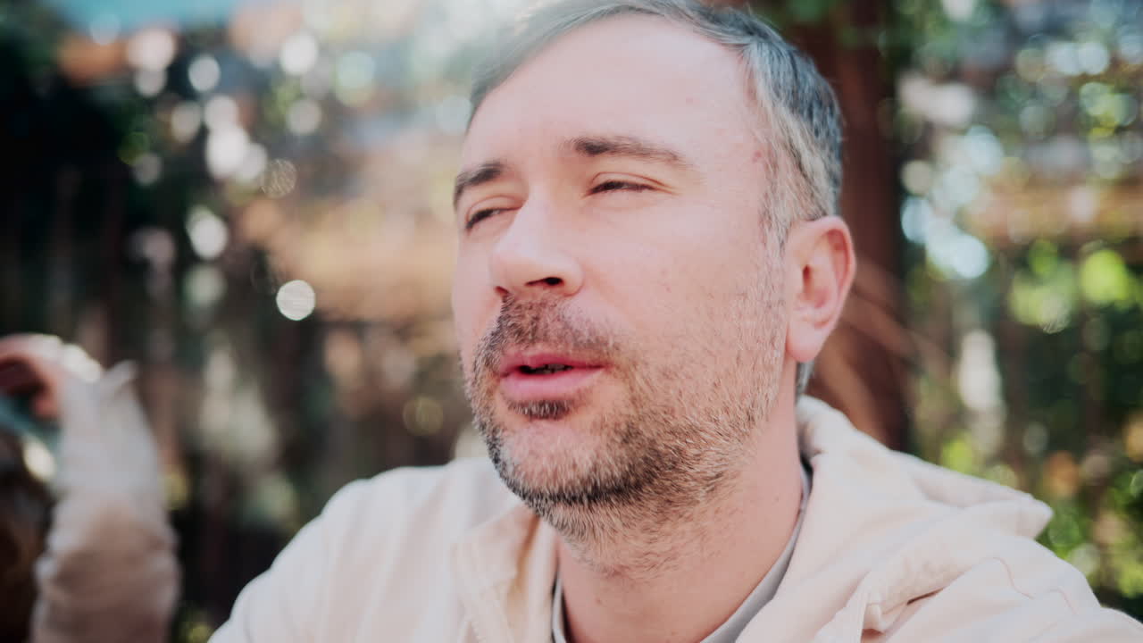 Close up of a man talking coffee in natural sunlight at a cozy outdoor cafe