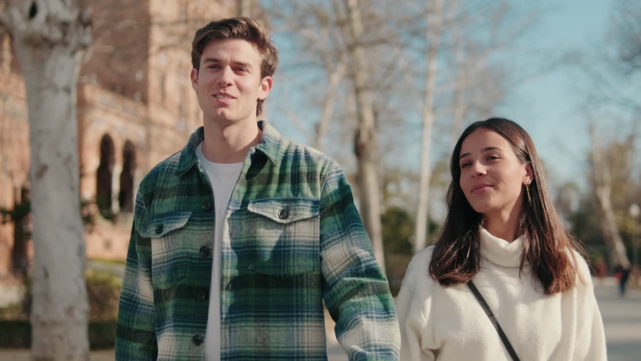 Happy young couple man and woman walking holding hands on the street