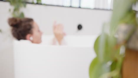 listening to music with wireless earbuds, woman relaxing in bathtub enjoying home time