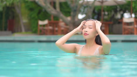 Sexy-exotic-female-model-in-swimming-pool-caresses-her-wet-hair,-full-frame-slow-moyion