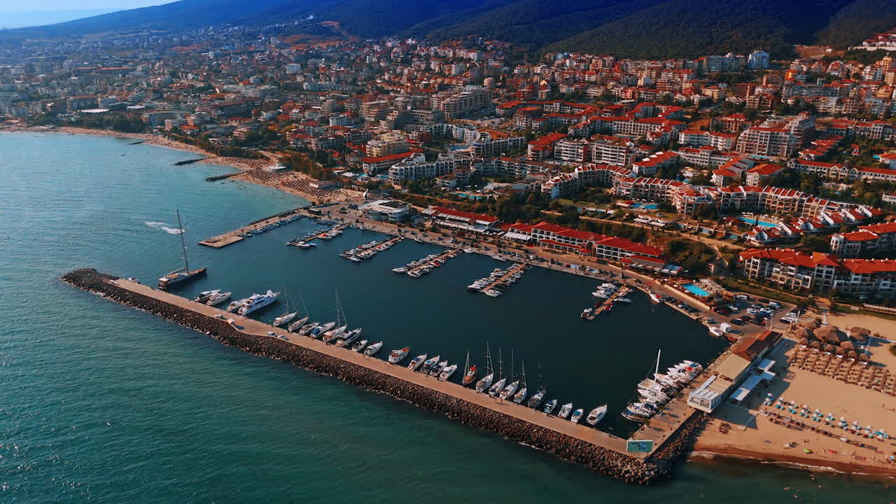Modern yachts stand at the berths near the coast of Bulgaria. Picturesque sea resort on the slopes of the mountains from drone footage