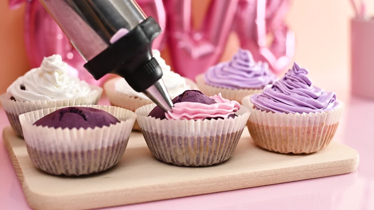 파스텔 분홍색 크림과 함께 벨 보라색 귀여운 컵 케이크를 장식합니다.