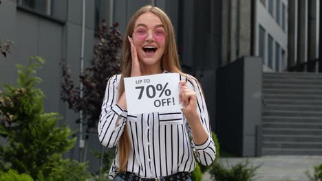 smiling girl showing up to 70 percent off inscriptions signs, rejoicing good discounts, low prices