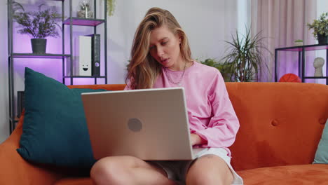 Young-woman-freelancer-sitting-on-sofa-closing-laptop-pc-after-finishing-work-in-living-room-at-home