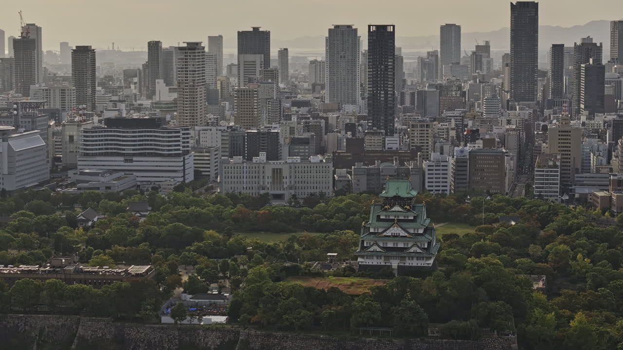 Osaka Japan Aerial v67 zoomed flyover the Osakajo park capturing the contrast of traditional Japanese castle against modern downtown cityscape at sunset - Shot with Mavic 3 Pro Cine - Oct 9th 2023