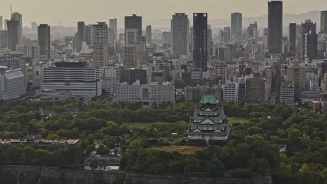 osaka japan aerial v67 zoomed flyover the osakajo park capturing the contrast of traditional japanese castle against modern downtown cityscape at sunset - shot with mavic 3 pro cine - oct 9th 2023