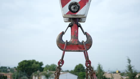 strong steel chained crane pulley with weathered red paint lifting heavy equipment