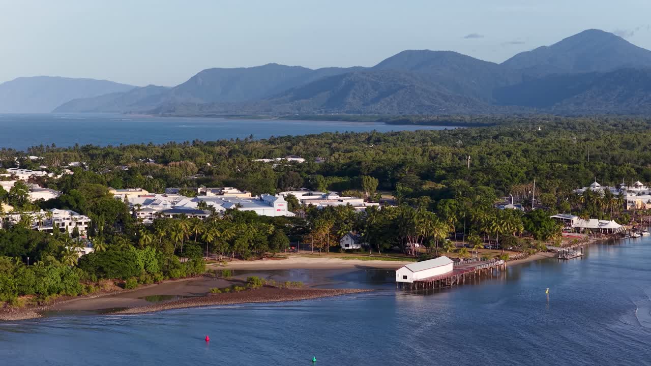 Drone footage captures Port Douglas' river, marina, and lush greenery under clear skies, highlighting the town's tropical charm