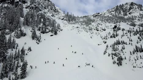 retreating aerial shot of snowy backcountry skiers in snoqualmie, wa