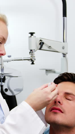 female optometrist putting eye drop in patient eyes