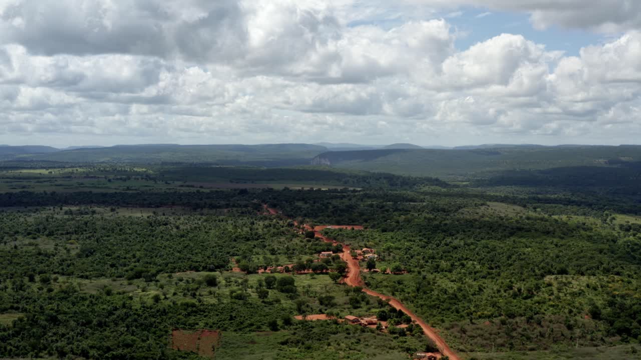 hermosa toma aérea con drones del campo brasileño con un pequeño camino de tierra roja en el parque nacional chapada diamantina en el norte de brasil y un soleado día de verano lleno de nubes