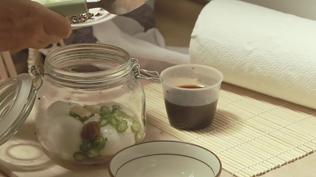 Adding cracked black pepper to a mason jar containing hard boiled eggs following the recipe for mayak gyeran or korean marinated eggs an authentic traditional local dish from Korea