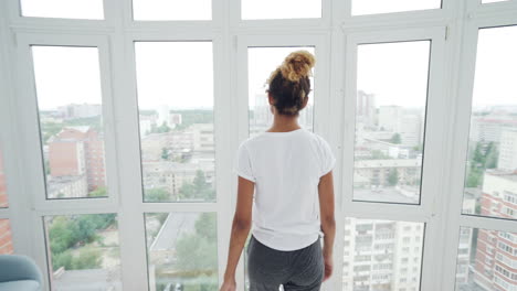 woman looking out at city view from window
