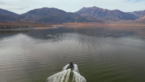 Wake surf surfing transfer water sports MB boat wave family activity Lake Crowley Mammoth Mountain Lakes California aerial drone golden still calm water morning sunny autumn fall clouds follow motion