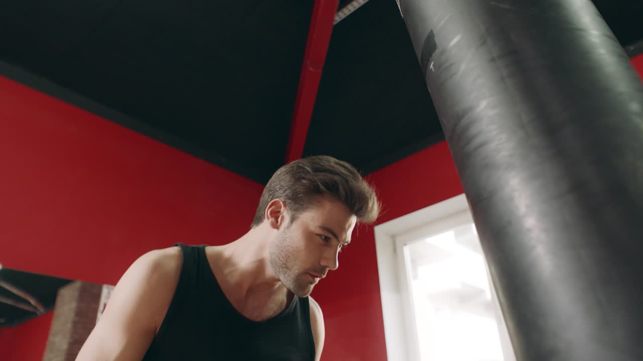 체육관에서 전투 가방을  ⁇ 고 있는 권투 선수.