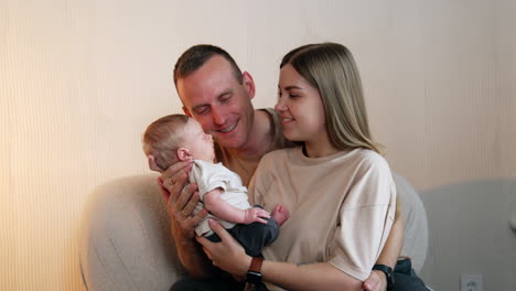 mom and dad hold their adorable newborn. loving father kisses his baby son on the head and leans to him.