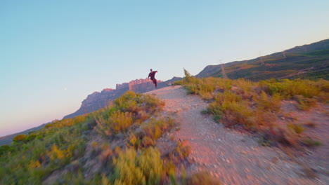 drone flying fast towards a breakdancer as the sun sets over the desert