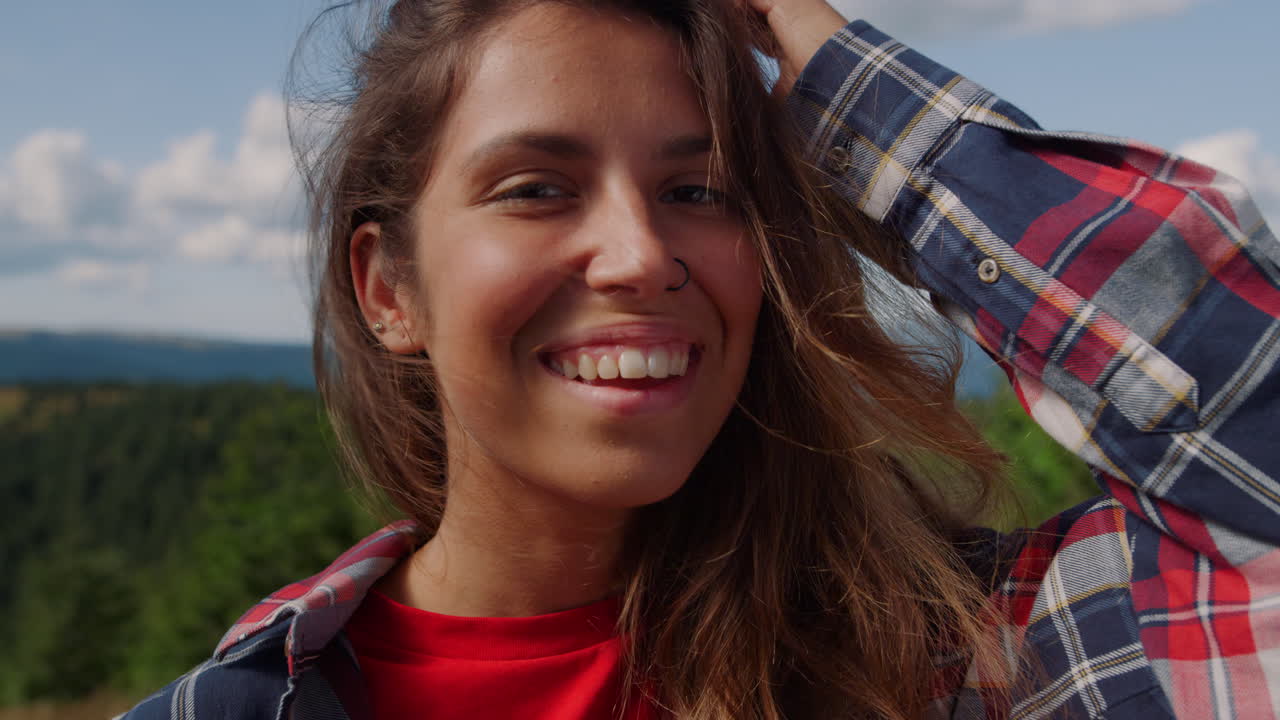 mujer alegre sonriendo en la cima de la montaña