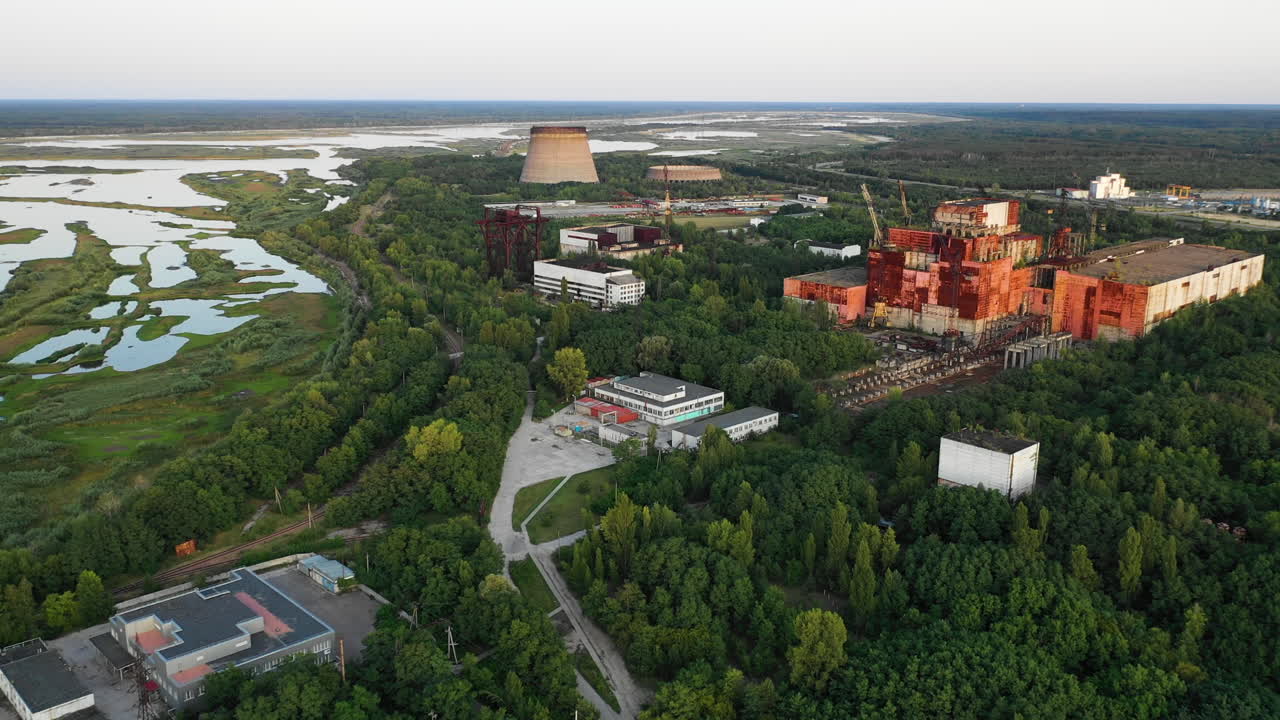 Aerial view captures desolate remains of Chernobyl's unfinished Reactor Blocks 5 and 6, surrounded by overgrown nature