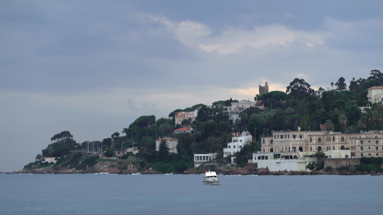 Boat floating on the sea with buildings and trees on the background
