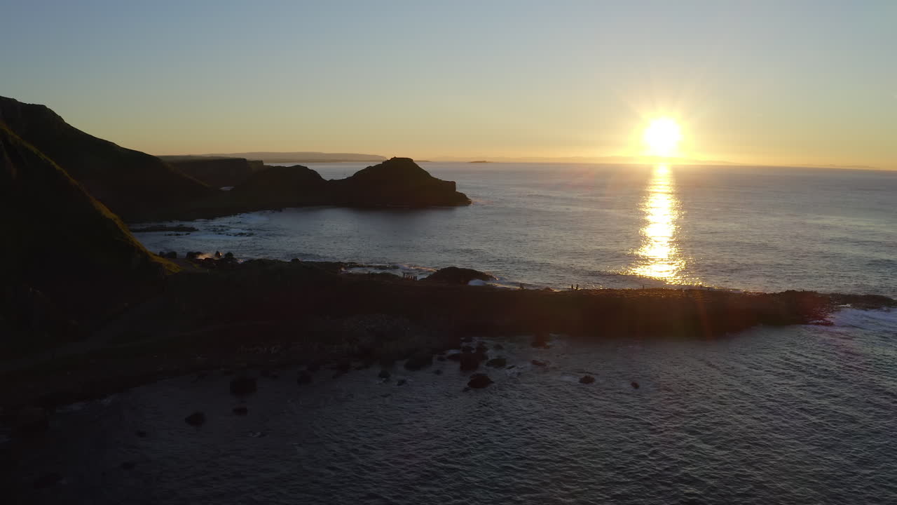High-angle aerial of Giant's Causeway with a warm sunset on the sea horizon
