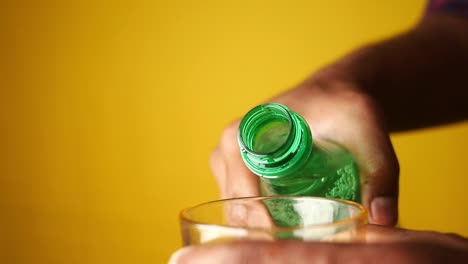 pouring a refreshing drink from a green bottle into a glass