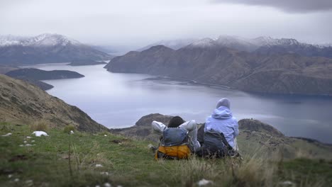 a couple over stunning moody panoramic views across lake wanaka in roy's peak in new zealand