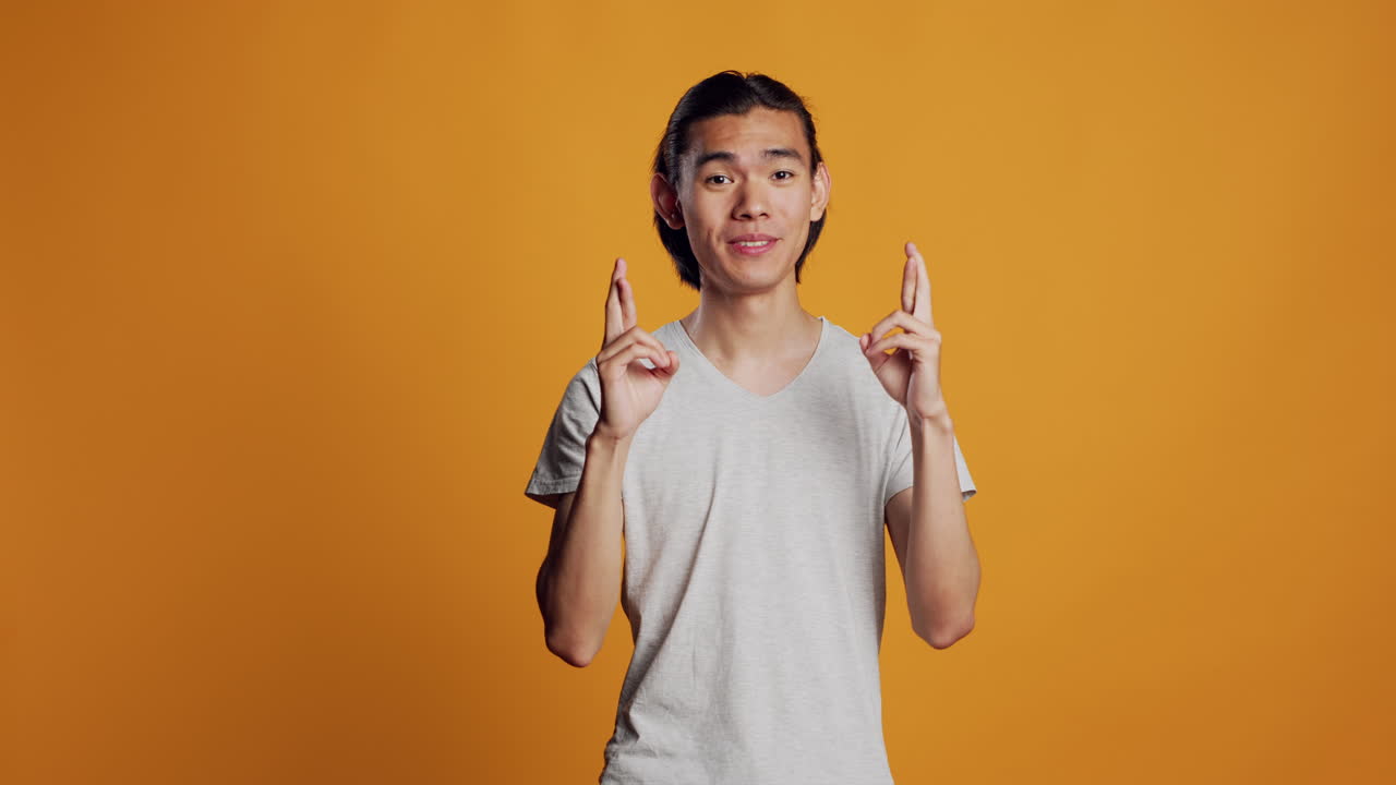 Hopeful positive guy posing with fingers crossed