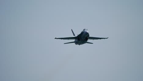 fighter jet soaring through clear blue sky, generating dramatic vapor trail while approaching camera in powerful slow motion shot, highlighting aerodynamic performance