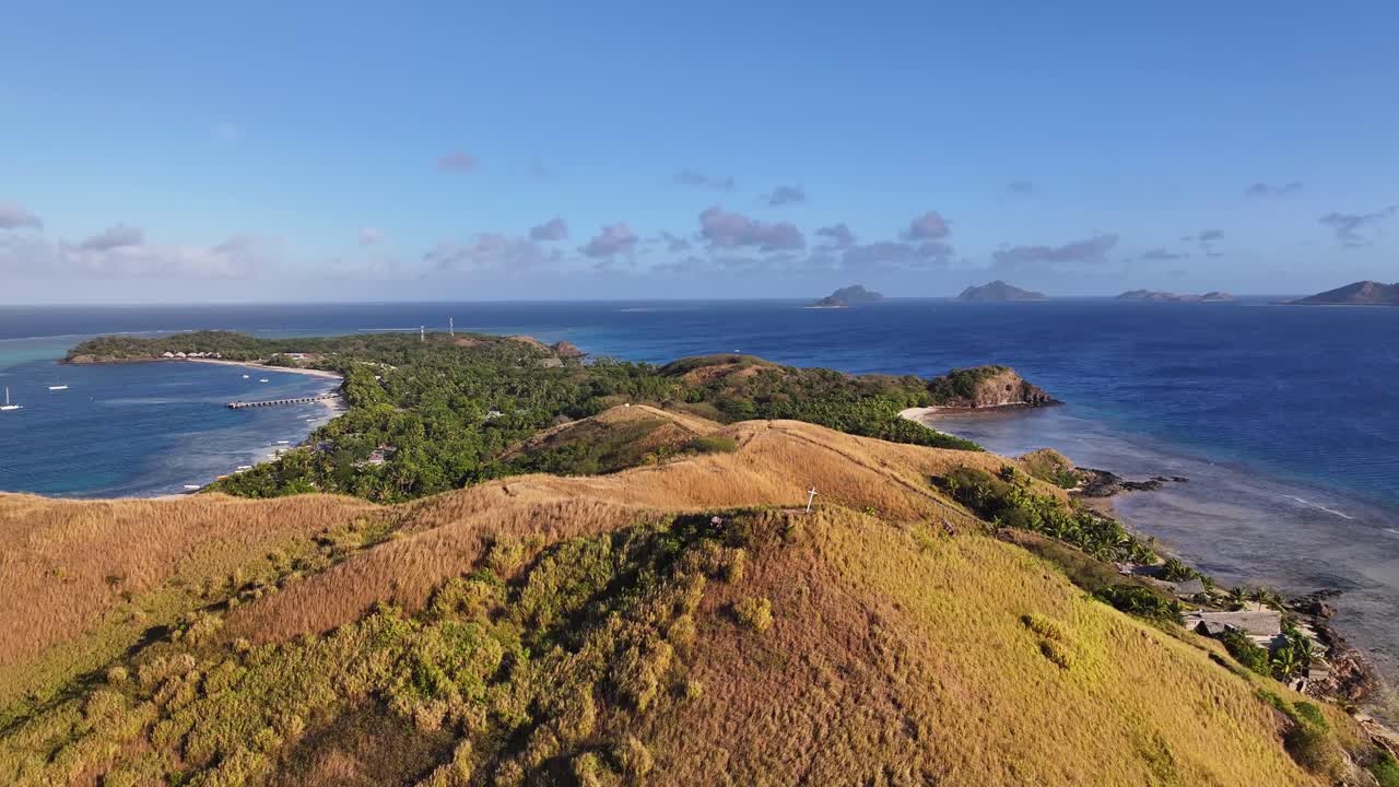 Drone pull back over the cross on top of the Mana Island, Fiji. Sunny holiday destination.