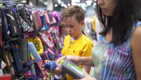woman with children in shop. little boy choosing school supplies with parents in stationery shop