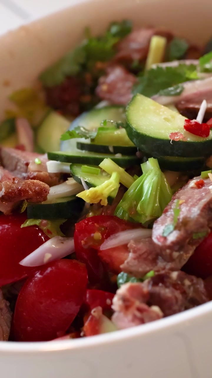Uma salada fresca de carne bovina com vegetais vibrantes é misturada em um ambiente de cozinha iluminado.