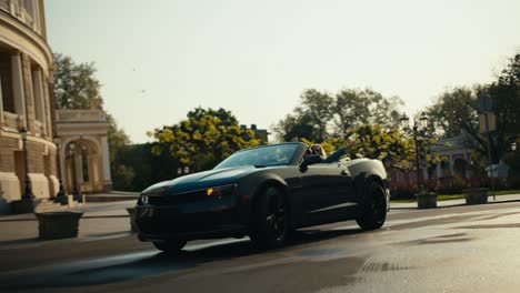 a beautiful gray dark gray cabriolet rides along the morning street, the girl in the back seat rejoices and spreads her arms