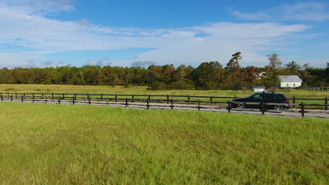 A-car-traveling-along-an-idyllic-back-road-setting-on-a-perfect-sky-blue-day