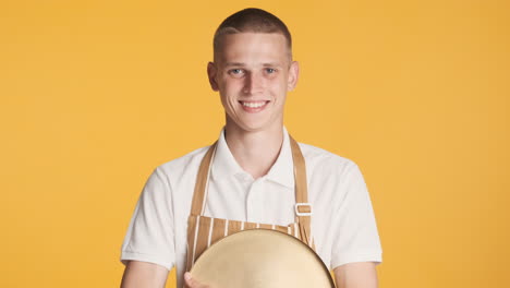 un joven rubio con uniforme de camarero sonriendo.
