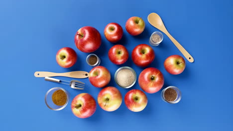 overhead view of apples and baking ingredients on blue background