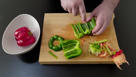 Rebanar-Un-Pimiento-Verde-En-Una-Tabla-Para-Cortar,-Tiro-Medio-Por-Encima-De-La-Cabeza